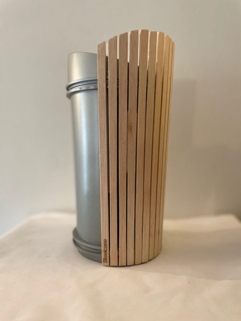 Objet cylindrique mêlant métal brossé et lattes de bois verticales, avec marquage Steelcase.