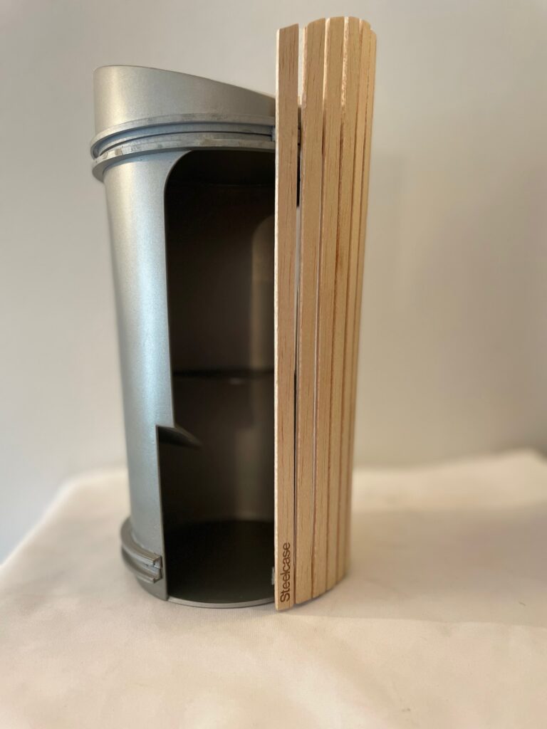 Maquette cylindrique en métal et bois avec ouverture latérale révélant une rampe intérieure et une plateforme.